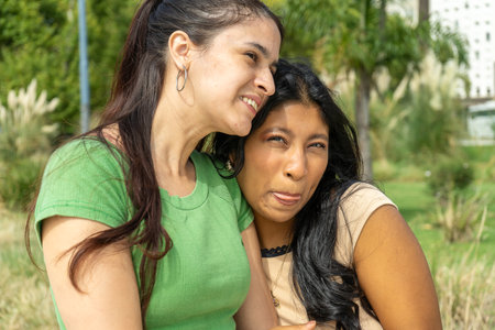 Two latin friends are enjoying their time together in a park, showing complicity and happinessの写真素材