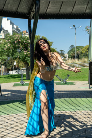 An Arab dancer in a blue dress with a golden scarf in the windの写真素材