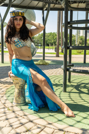 An Arab dancer in a blue dress sitting on a Darbuka in the shadowsの写真素材