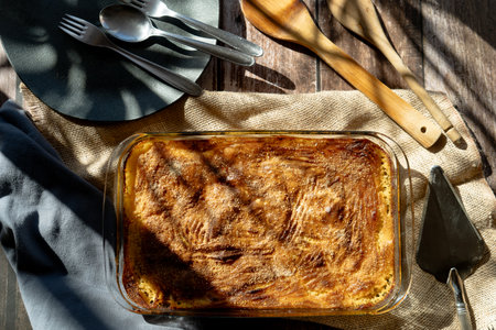 A Glass platter with a meat or shepherd's pie on a rustic country table.