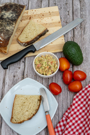 Preparing fresh guacamole with rustic bread and tomatoesの写真素材