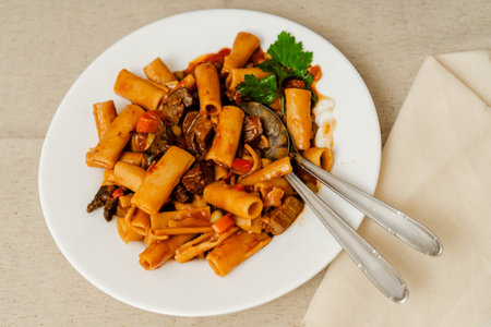 White plate with beef stew and rigatoni pasta, creating an enticing culinary sceneの写真素材