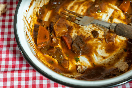 Plate with leftover beef stew on a red checkered cloth