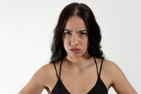 Young latin woman expressing anger and frustration on white backgroundの写真素材