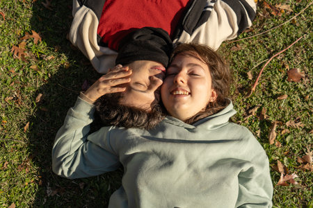 Young couple relaxing together on grass in autumn sunlightの写真素材
