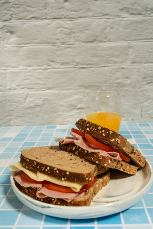 Two natural ham and cheese sandwiches on multigrain bread with fresh juiceの写真素材