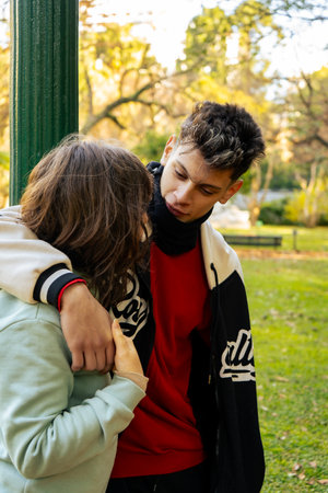 Young man comforting his girlfriend in a park during autumnの写真素材