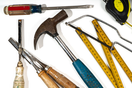 Claw hammer, chisels, screwdriver, measuring tape and folding ruler lying on a white background,...