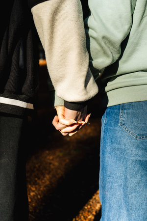Romantic couple holding hands while enjoying a walk in a forest, symbolizing their love, connection, and shared journeyの写真素材