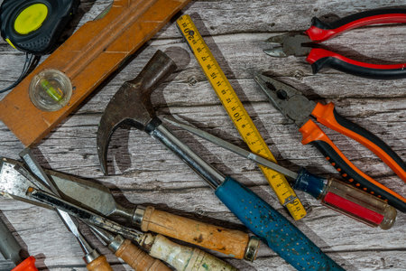 Claw hammer, chisels, pliers, screwdriver, folding ruler, tape measure and spirit level are lying on...
