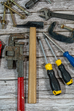 Various tools including hammer, screwdrivers, wrench and other tools lying on wooden table, top view