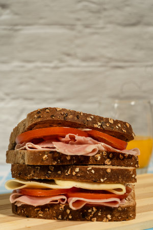 Front view of two ham and tomato sandwiches with whole grain toasted bread and orange juiceの写真素材