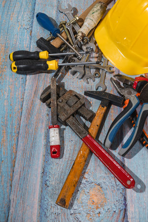 Variety of construction tools lying on wooden surface with yellow helmet, ready for building workの写真素材