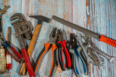 Different work tools such as wrenches, hammer, pliers, screwdriver and rasp lying on old wooden planksの写真素材