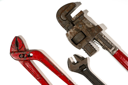 Old rusty and red tools lying on a white background, ready to be used for plumbing workの写真素材