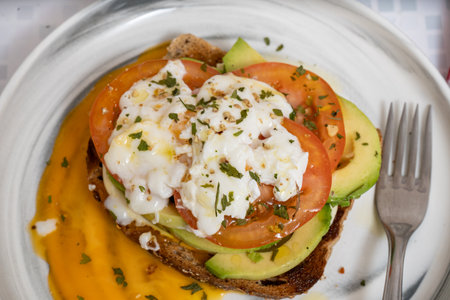 Rustic bread topped with avocado, tomato, and creamy mozzarellaの写真素材