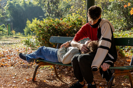 Romantic couple enjoying a peaceful moment together on a park bench, surrounded by colorful autumn foliageの写真素材