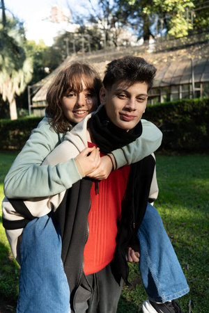 Happy couple having fun outdoors in a park, enjoying a piggyback ride on a sunny dayの写真素材