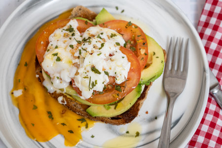 Sliced avocado and tomato on rustic bread with a poached eggの写真素材