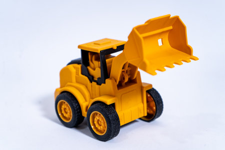 Yellow toy excavator lifting bucket on white backgroundの写真素材
