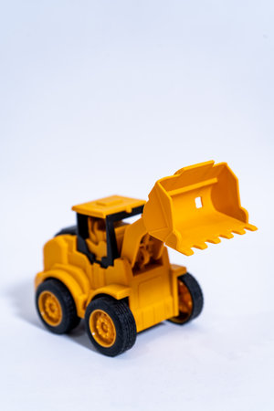 Yellow toy excavator lifting bucket on white background