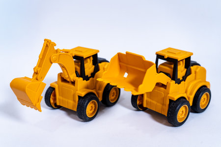 Two yellow toy excavators resting on white background