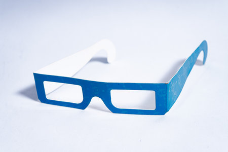 Cyan and white anaglyph 3d glasses are laying on a white surface, ready for viewing stereoscopic images and moviesの写真素材