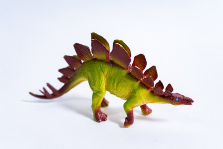 Plastic stegosaurus dinosaur toy standing on a white background, evoking childhood and imaginative playの写真素材