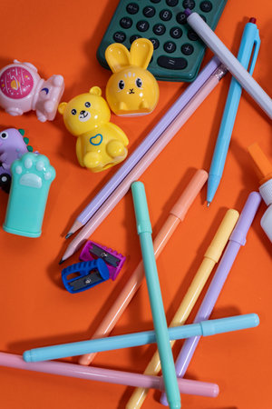 Pastel-colored pens, pencils, erasers, sharpeners, and a calculator create a cheerful back-to-school...