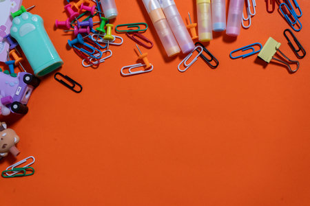 Flat lay composition of colorful school supplies creating copy space on a vibrant orange background, perfect for back-to-school promotionsの写真素材