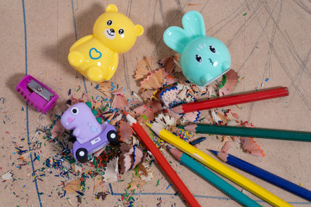 Colorful pencil shaves surround colored pencils and fun pencil sharpeners on a piece of cardboardの写真素材