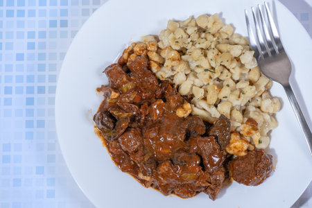 Steaming hot Hungarian goulash served with spaetzle dumplings, creating a hearty and flavorful mealの写真素材