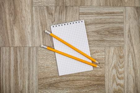 Note book with yellow pencil on a wooden texture