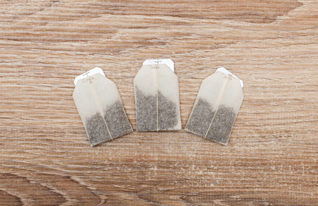 Three unused teabags in a row on wooden backgroundの写真素材
