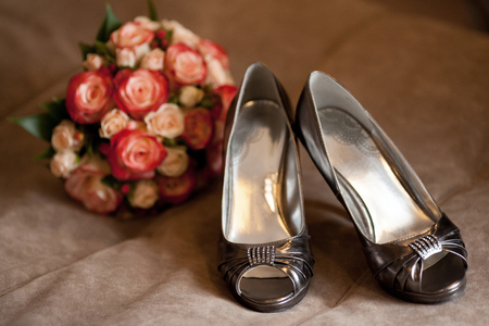 Stylish dark bridal wedding shoes with rose bouquet on sofa. Marriage conceptの写真素材