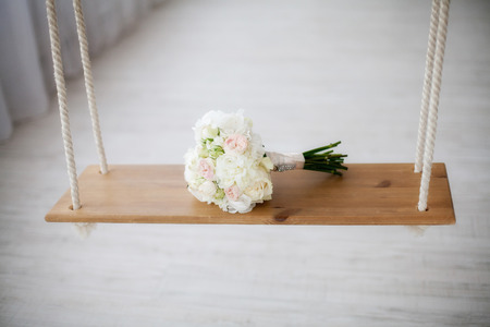 Beautiful white peony wedding bouquet on wooden swing. Marriage conceptの写真素材