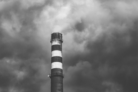 Big smoking industrial chimney in dark clouds. Black and white photo. Environmental protection conceptの写真素材