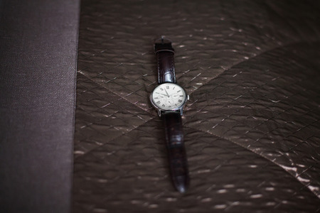 Men's watch with dark leather strap on sofa