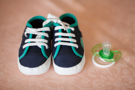 Small baby booties and dummy on a sofaの写真素材