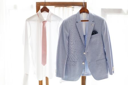 White shirt with necktie and gray suit of groom hanging on hanger, wedding clothingの写真素材