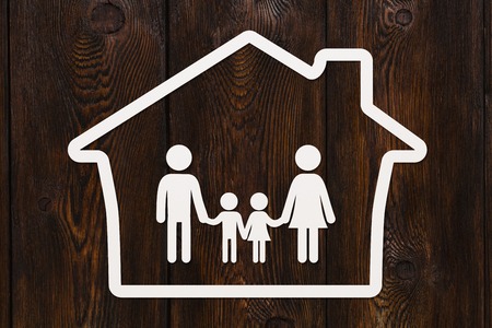 Paper man, woman, children in house. Family concept. Abstract conceptual image. Dark wooden backgroundの写真素材