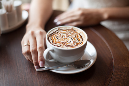 Hands of bride with latte art coffee cup. Selective focus, close-upの写真素材