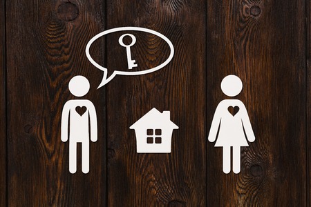 Paper woman and man thinking about a key of house. Dark wooden background. Housing, family concept. Abstract conceptual imageの写真素材