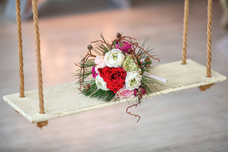 Wedding bouquet of artificial flowers on wooden swing. Marriage conceptの写真素材