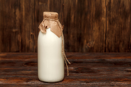 Bottle of milk on rustic wooden table with copyspaceの写真素材