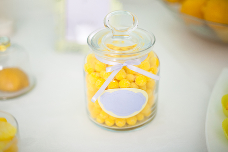 Yellow lemon candy in a glass jar on sweet tableの写真素材