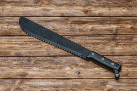 Machete for cutting grass on brown wooden background