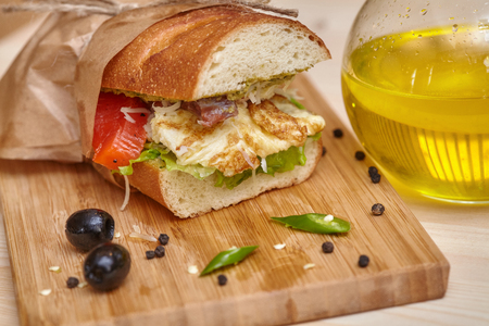 Big bread sandwich on wooden cutting board with ingridients, closeupの写真素材