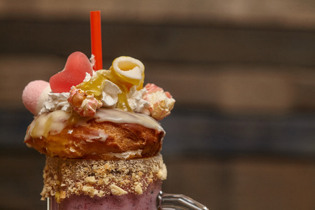 Caramel marshmallow candy milk shake cocktail with whipped cream, cookies, waffles and other treats, closeupの写真素材
