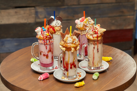 Group of caramel marshmallow candy milk shake cocktails with whipped cream, cookies, waffles and other treatsの写真素材
